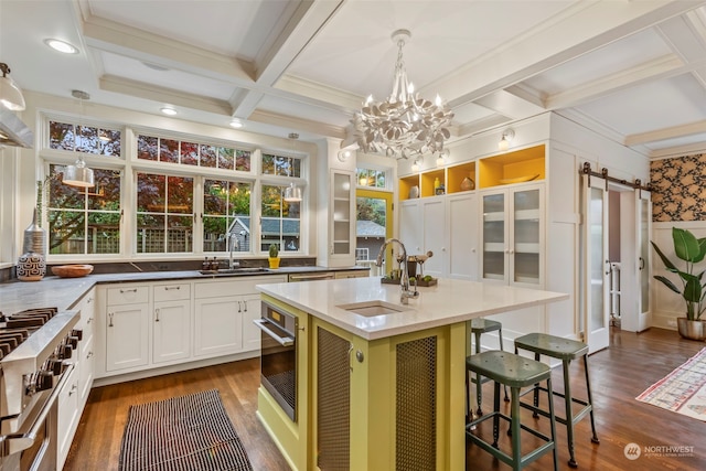 kitchen with a center island with sink, white cabinets, a barn door, pendant lighting, and dark hardwood / wood-style flooring