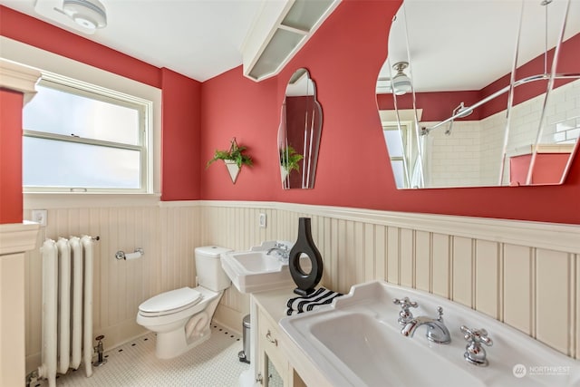 bathroom with toilet, radiator heating unit, sink, and tile patterned flooring