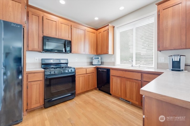 kitchen with light hardwood / wood-style flooring, black appliances, and sink