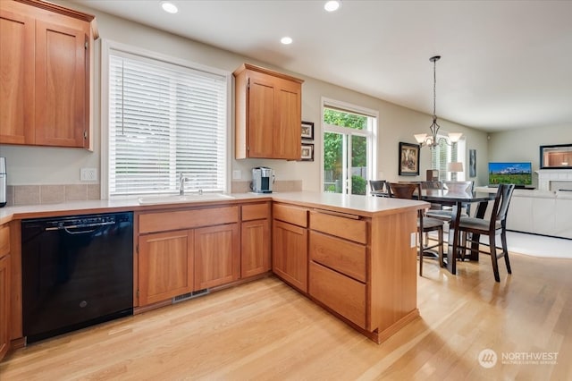 kitchen with light hardwood / wood-style floors, black dishwasher, kitchen peninsula, hanging light fixtures, and sink