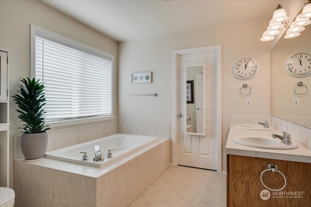 bathroom featuring tiled tub, vanity, and plenty of natural light