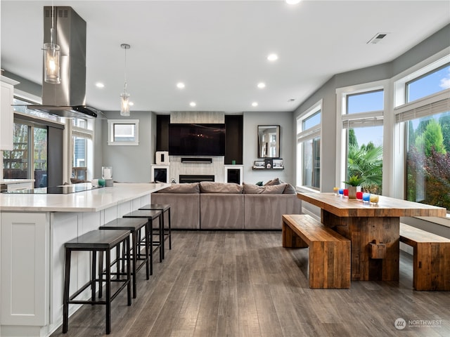 kitchen featuring dark wood-type flooring, black electric stovetop, pendant lighting, island exhaust hood, and white cabinetry