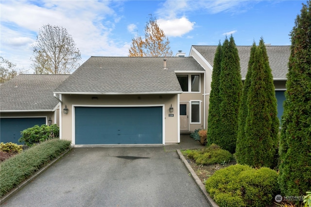 view of front facade with driveway, a shingled roof, an attached garage, and stucco siding