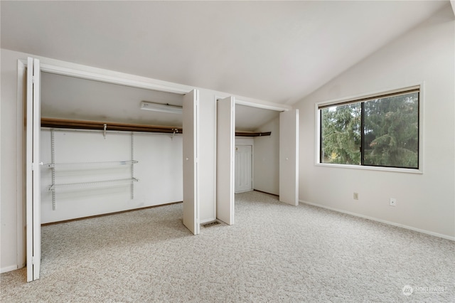 unfurnished bedroom with multiple closets, vaulted ceiling, carpet floors, and baseboards