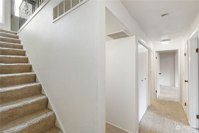 interior space featuring carpet, visible vents, and stairway