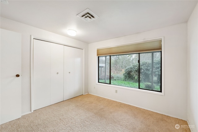 unfurnished bedroom with carpet, visible vents, and a closet