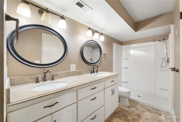 bathroom featuring toilet, walk in shower, a sink, and visible vents