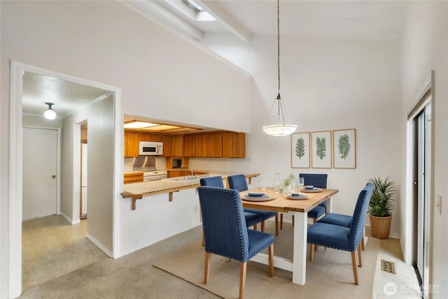 dining room featuring light carpet, baseboards, high vaulted ceiling, and beamed ceiling