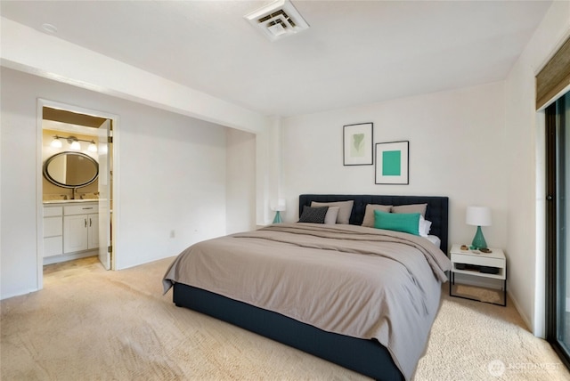 carpeted bedroom with visible vents and connected bathroom