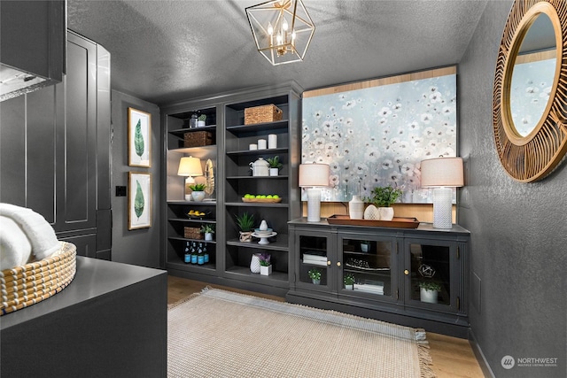 interior space with a textured ceiling, light wood-type flooring, and a notable chandelier