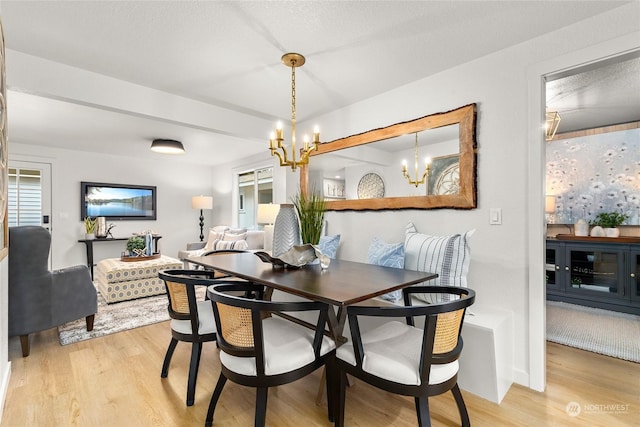 dining area with a chandelier, a textured ceiling, and light wood-type flooring