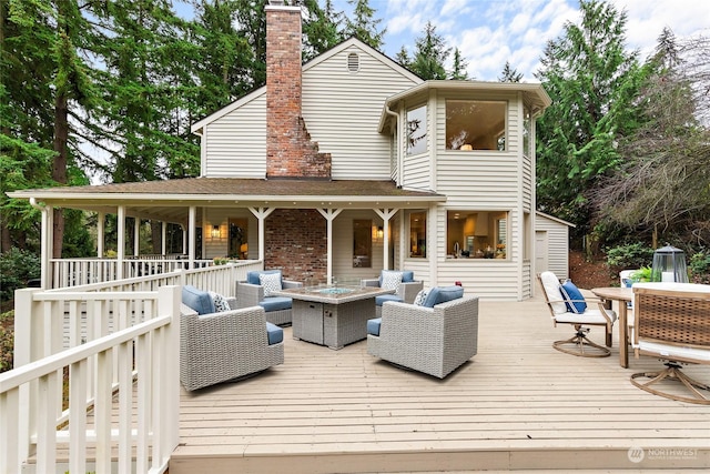 back of property featuring a deck and an outdoor living space with a fire pit