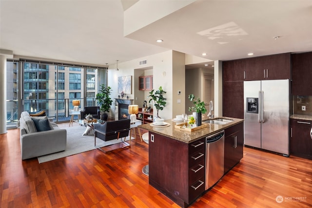 kitchen featuring appliances with stainless steel finishes, sink, light hardwood / wood-style floors, and a kitchen island with sink