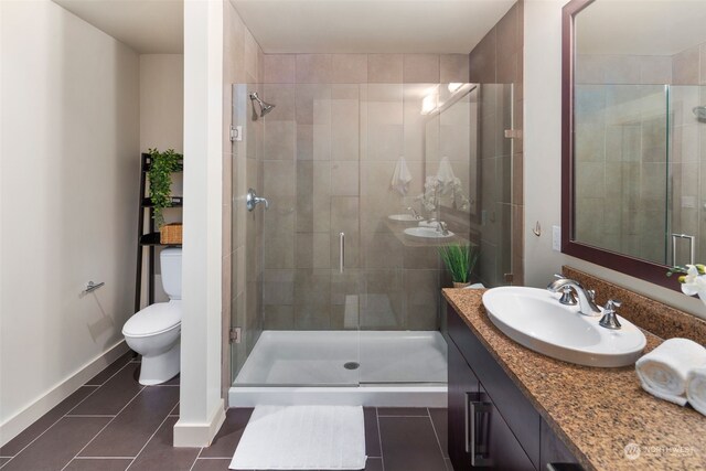 bathroom with toilet, vanity, tile patterned floors, and a shower with shower door