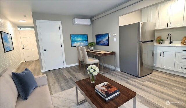 living room with sink, light hardwood / wood-style flooring, and a wall mounted AC