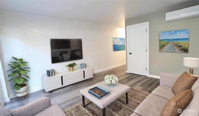 living room with hardwood / wood-style floors, an AC wall unit, and brick wall