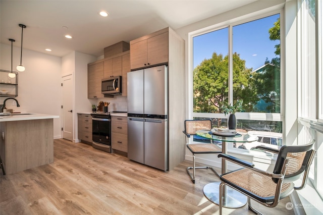 kitchen with sink, decorative light fixtures, light hardwood / wood-style floors, and stainless steel appliances