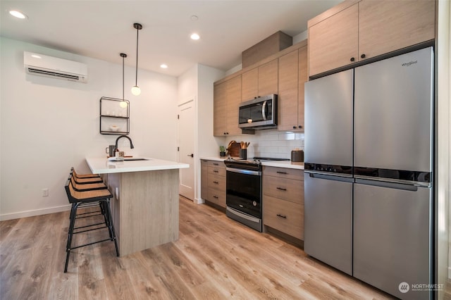 kitchen with stainless steel appliances, a wall mounted AC, sink, and light hardwood / wood-style flooring