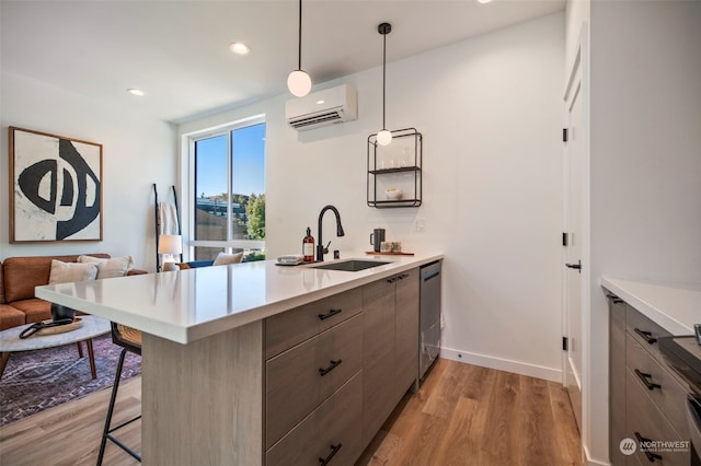 kitchen featuring sink, kitchen peninsula, a wall mounted air conditioner, a breakfast bar area, and pendant lighting