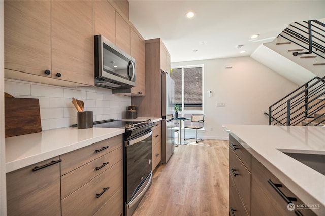 kitchen featuring tasteful backsplash, light wood-type flooring, and appliances with stainless steel finishes