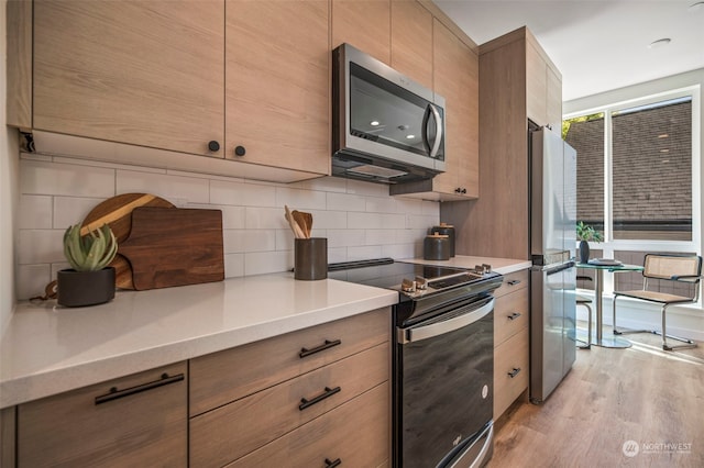 kitchen featuring decorative backsplash, light wood-type flooring, and appliances with stainless steel finishes