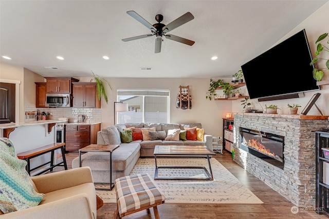 living room featuring a fireplace, hardwood / wood-style floors, and ceiling fan