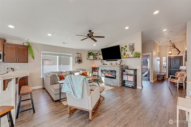 living room with ceiling fan, a fireplace, and wood-type flooring