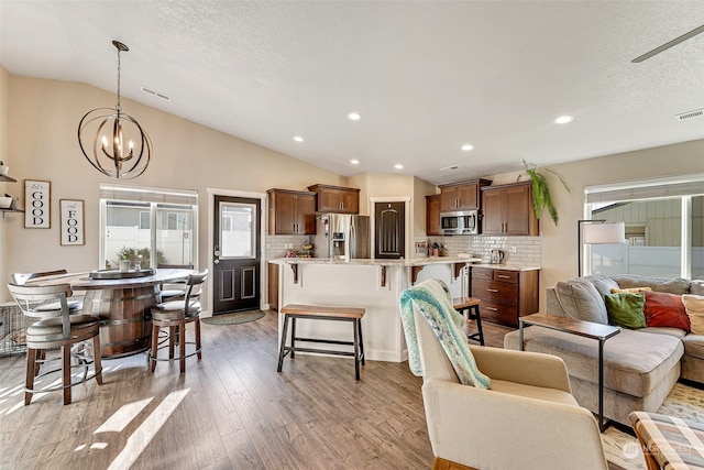 living room featuring a textured ceiling, light hardwood / wood-style flooring, and lofted ceiling