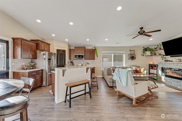 living room with a fireplace, light wood-type flooring, ceiling fan, and sink