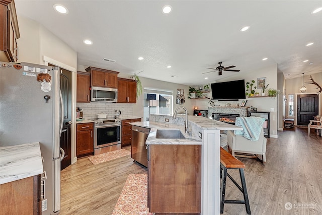 kitchen with appliances with stainless steel finishes, light hardwood / wood-style floors, a breakfast bar area, and sink