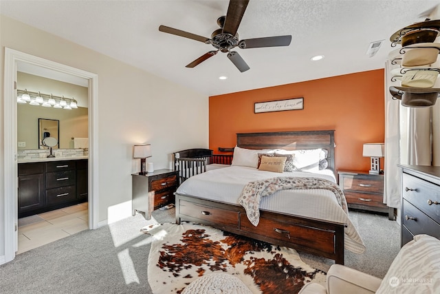 bedroom featuring a textured ceiling, ceiling fan, light carpet, and ensuite bath