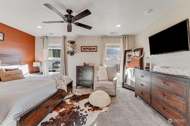 bedroom with multiple windows, ceiling fan, and light carpet