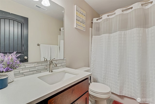 bathroom with vanity, toilet, and tasteful backsplash