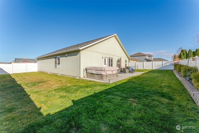 back of property with a yard, a hot tub, and a patio area