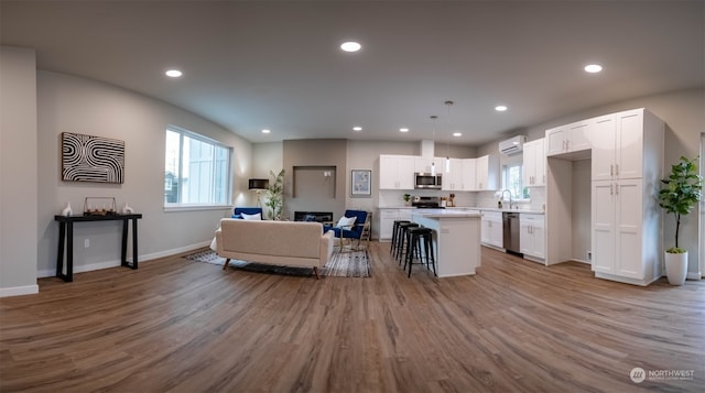 kitchen with white cabinetry, a breakfast bar, hanging light fixtures, a center island, and stainless steel appliances