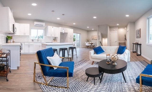 living room with a wealth of natural light, light hardwood / wood-style floors, and a wall unit AC