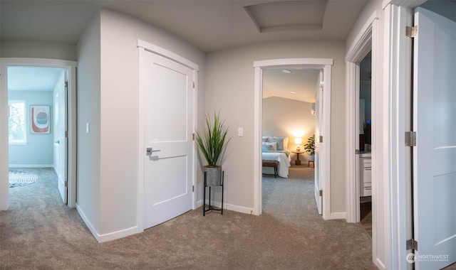 hall with light carpet and vaulted ceiling