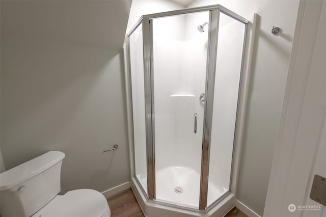 bathroom with an enclosed shower, toilet, and hardwood / wood-style floors