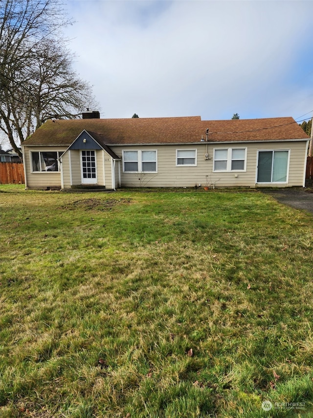 rear view of property featuring a lawn