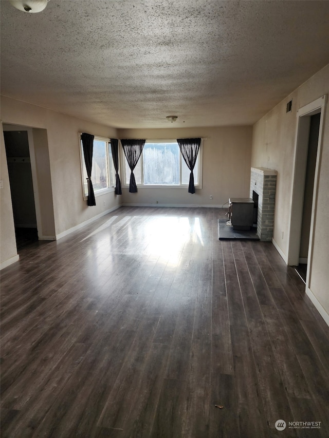 unfurnished living room featuring a textured ceiling, a wood stove, and dark wood-type flooring