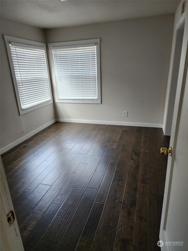 spare room featuring dark hardwood / wood-style flooring and a textured ceiling