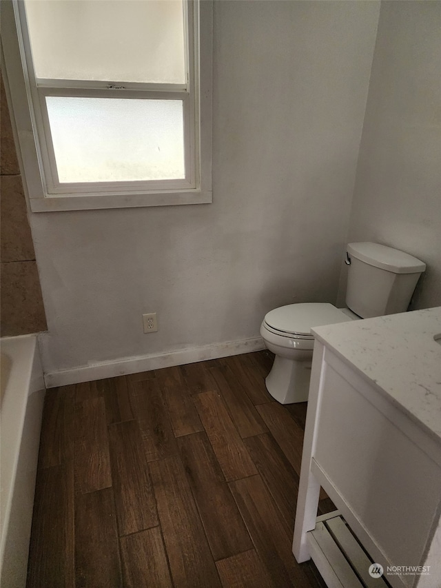 bathroom with hardwood / wood-style flooring, vanity, a bathtub, and toilet