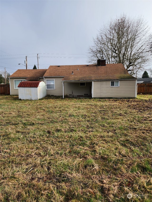 back of house with a lawn and a storage shed