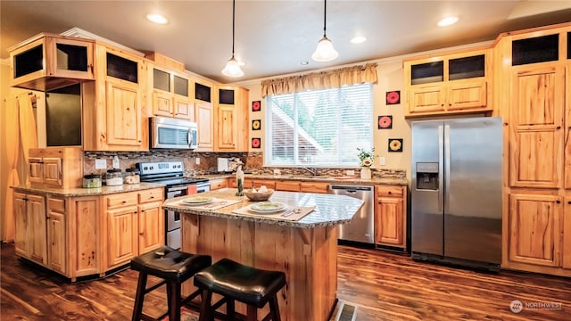 kitchen featuring stainless steel appliances, hanging light fixtures, dark hardwood / wood-style floors, a kitchen island, and light stone countertops