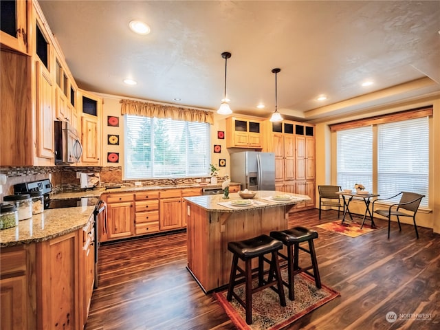 kitchen with stainless steel appliances, dark wood-type flooring, light stone counters, tasteful backsplash, and a kitchen island