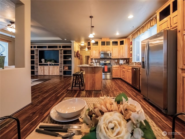 kitchen featuring dark hardwood / wood-style flooring, decorative light fixtures, appliances with stainless steel finishes, and a center island