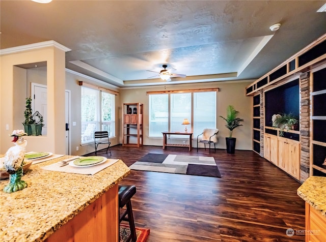 living room featuring dark wood-type flooring, a tray ceiling, a textured ceiling, and ceiling fan