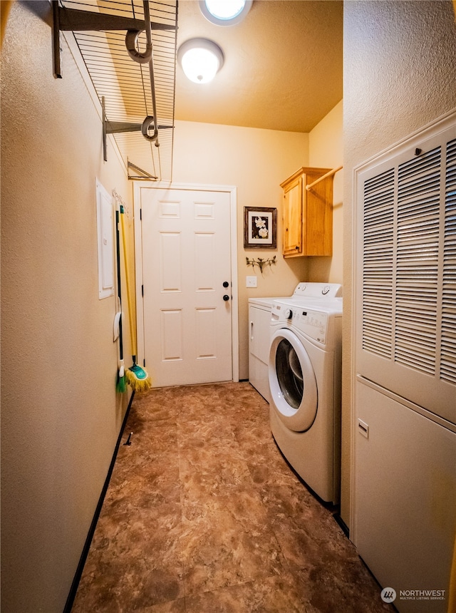 clothes washing area with cabinets and washer and clothes dryer