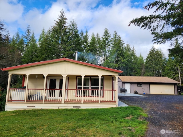 view of front of home with an outbuilding, a porch, a front yard, and a garage