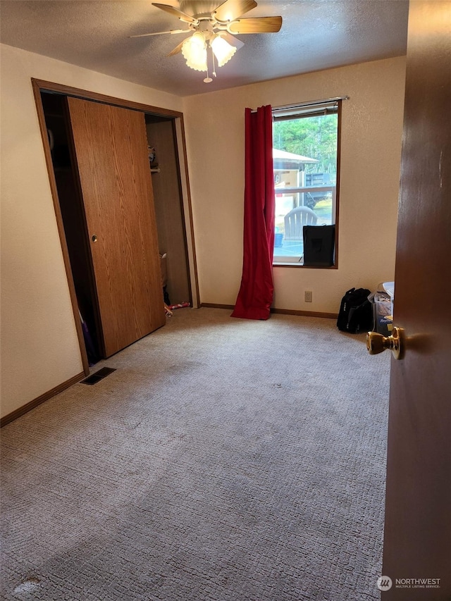 unfurnished bedroom with ceiling fan, carpet flooring, a closet, and a textured ceiling